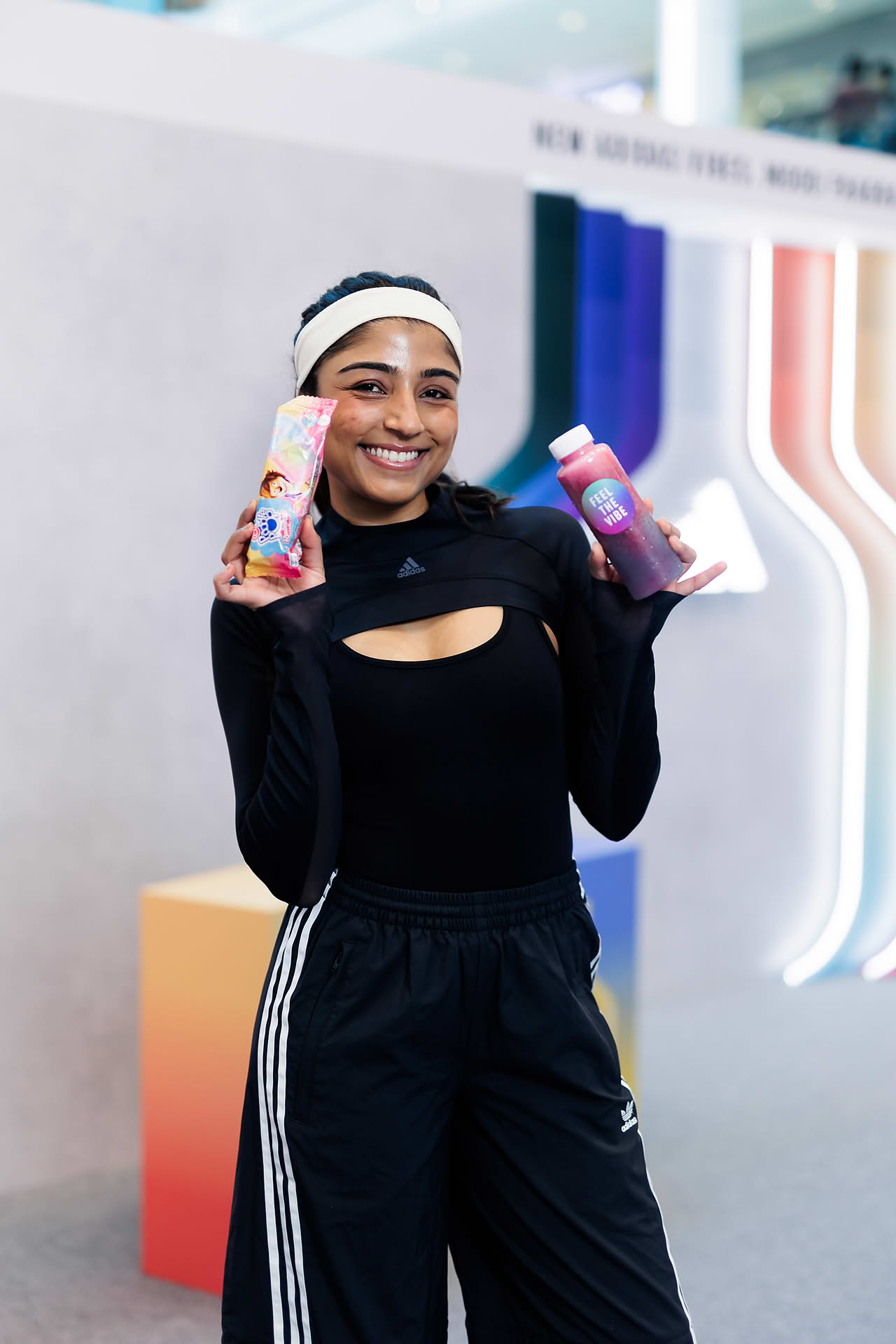 Influencer holding up drinks served at Addidas Vibe pop-up stall in Plaza Singapura