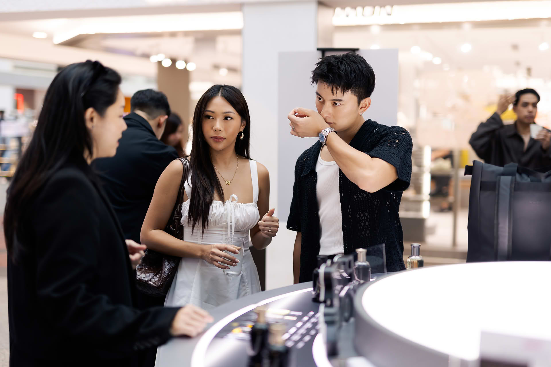 Actor smelling perfume at BOSS pop-up stall in Bugis Junction