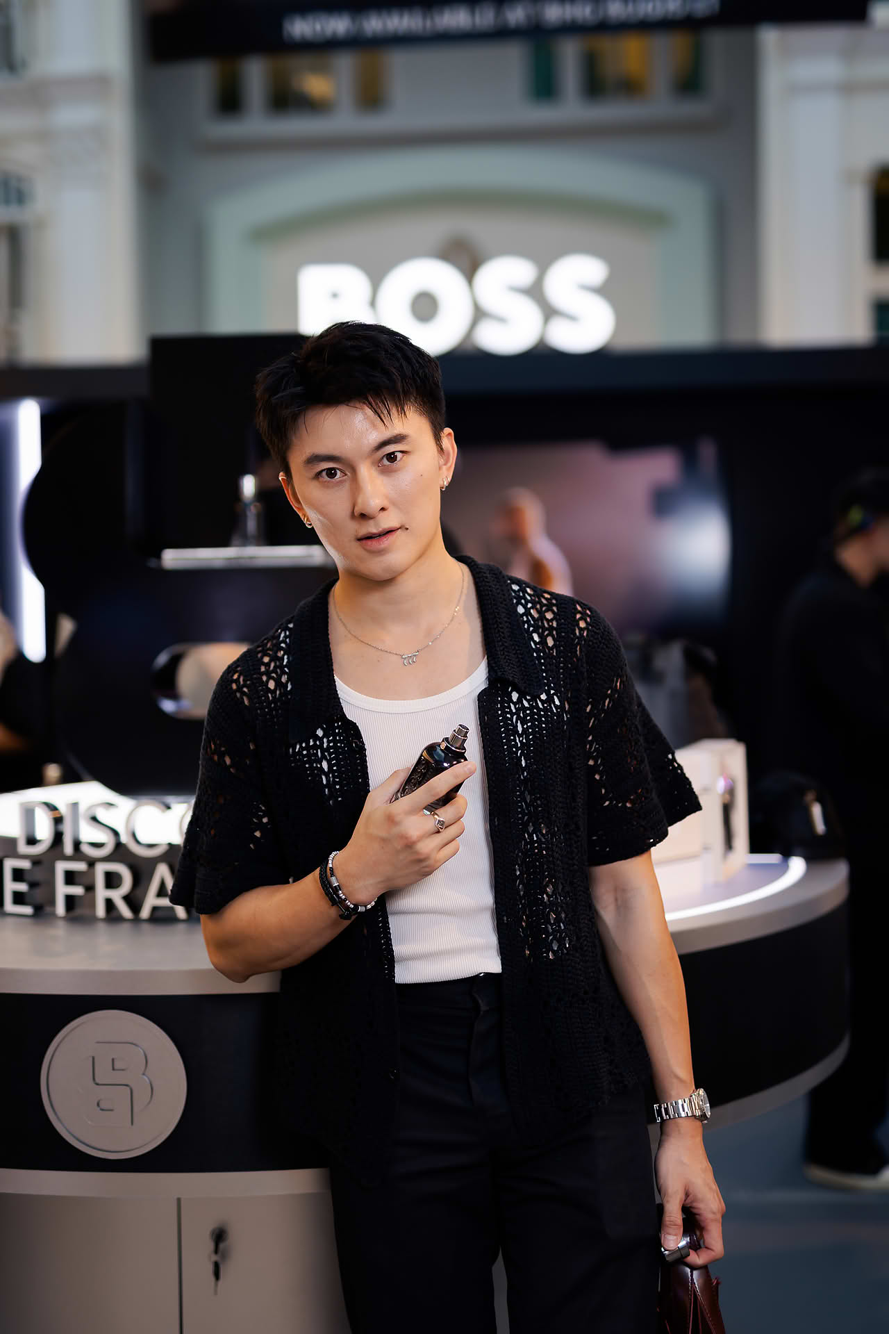 Actor posing with perfume at BOSS pop-up stall in Bugis Junction