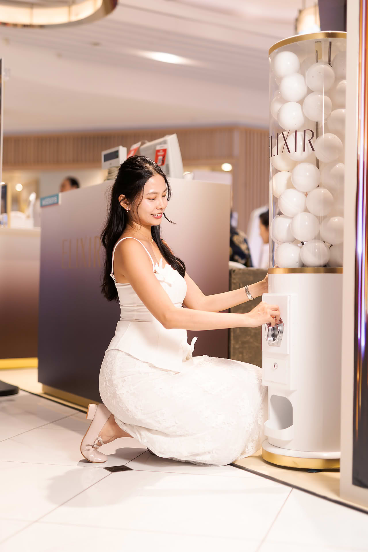 Model playing gacahpon machine at Exlixir pop-up stall in Ngee Ann City