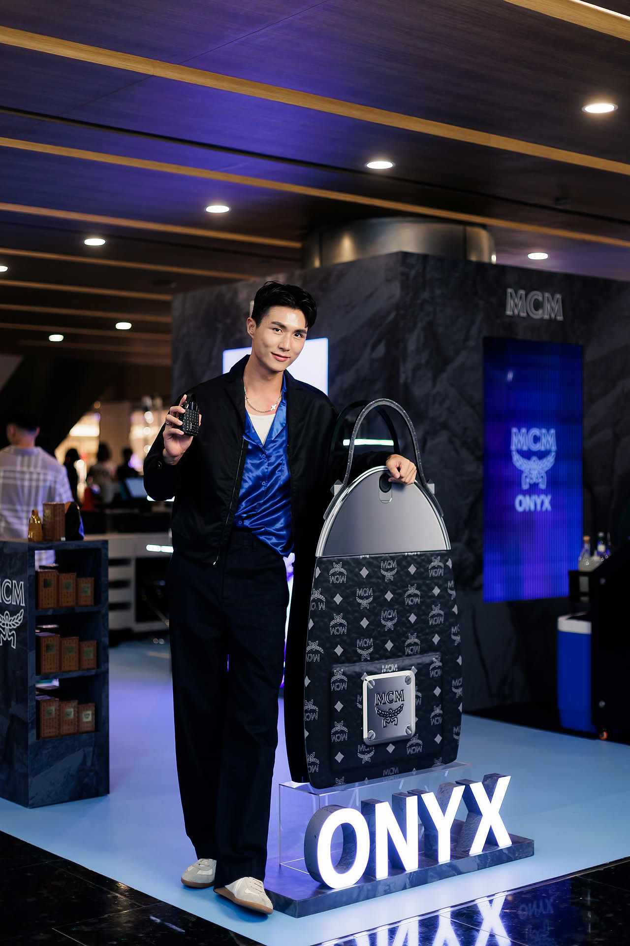 Influencer posing with perfume at MCM pop-up stall at Paragon